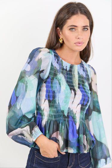 Woman wearing a colorful floral blouse against a white background