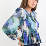 Woman wearing a colorful blouse with long sleeves on a white background
