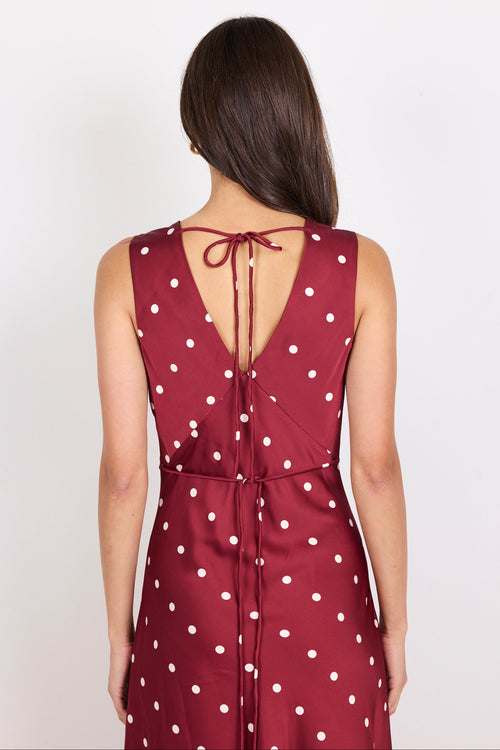 Woman wearing a red dress with white polka dots on a plain background