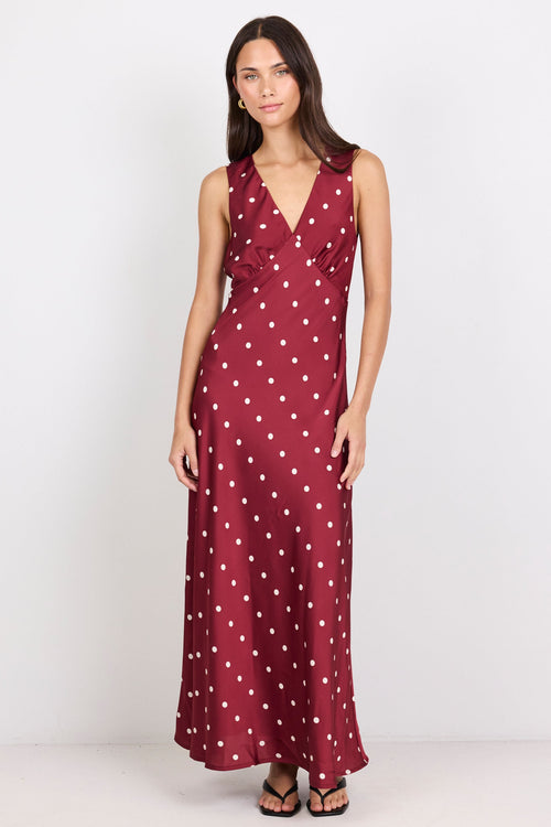 Woman wearing a burgundy dress with white polka dots on a white background