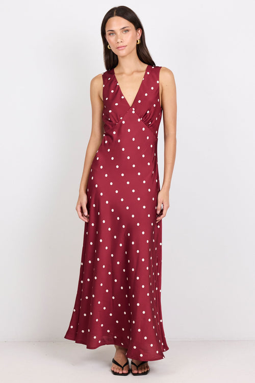 Woman wearing a burgundy dress with white polka dots on a white background