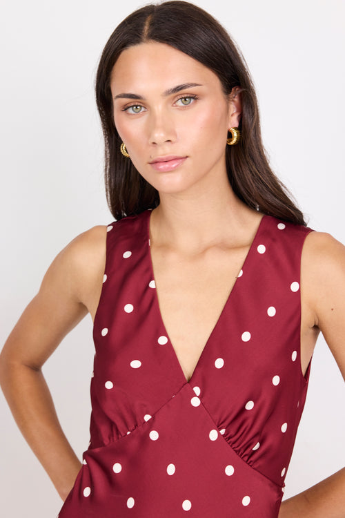Woman wearing a red dress with white polka dots against a plain background