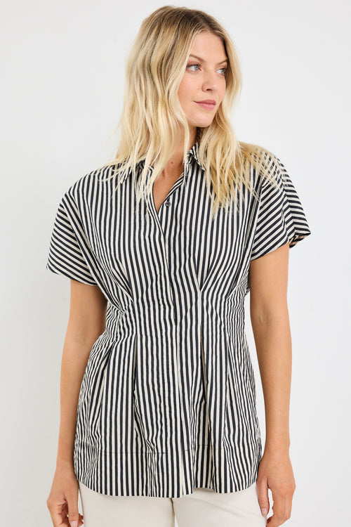 model wears a black and white short sleeve corset shirt with white jeans