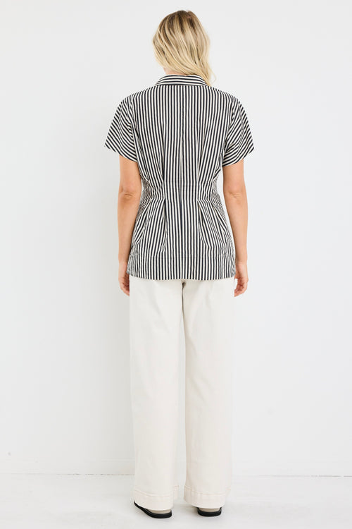 model wears a black and white short sleeve corset shirt with white jeans