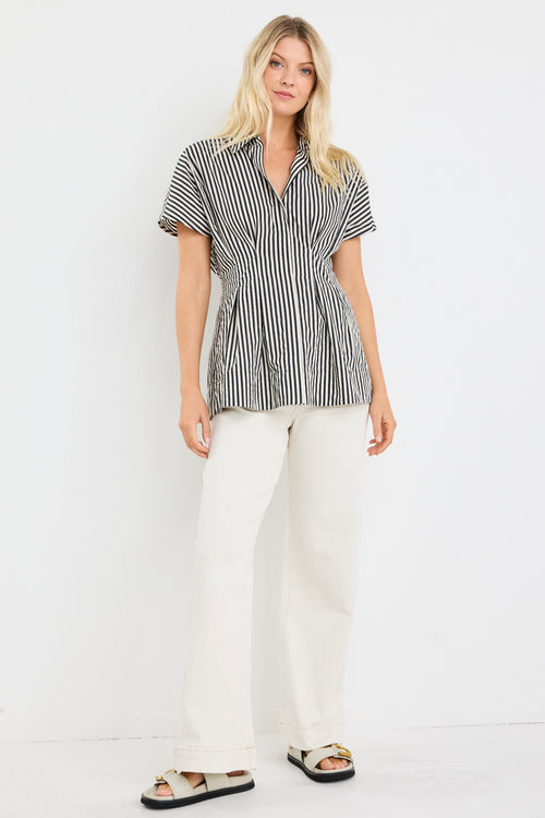 model wears a black and white short sleeve corset shirt with white jeans