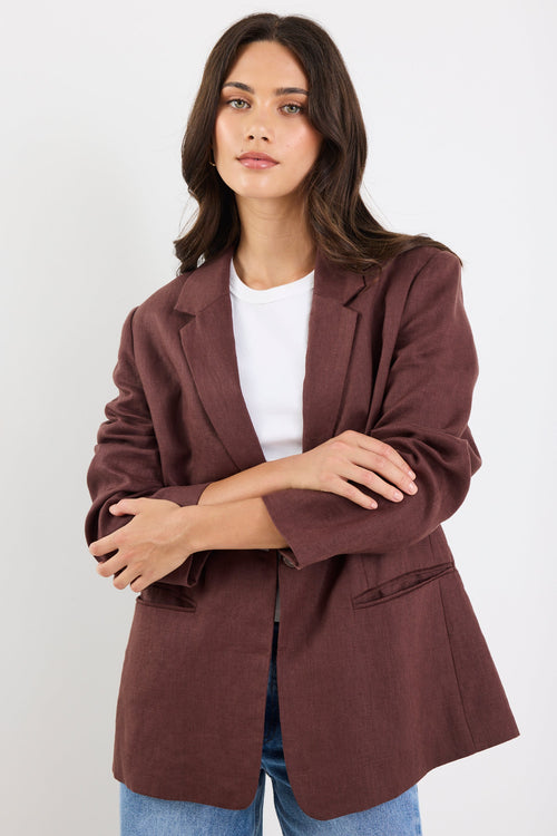 Woman wearing a brown blazer over a white shirt on a white background