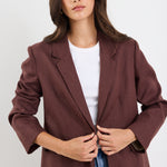 Woman wearing a brown blazer over a white shirt on a white background