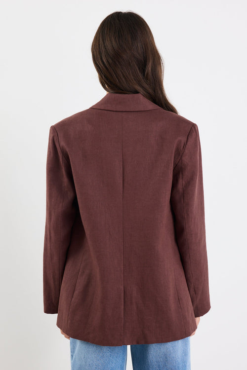 Person wearing a brown blazer and blue jeans on a white background