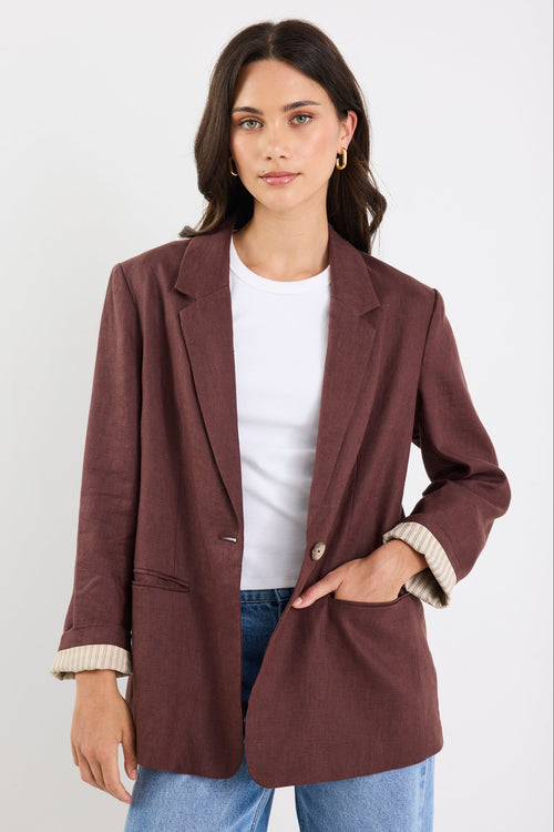 Woman wearing a brown blazer over a white shirt with a white background