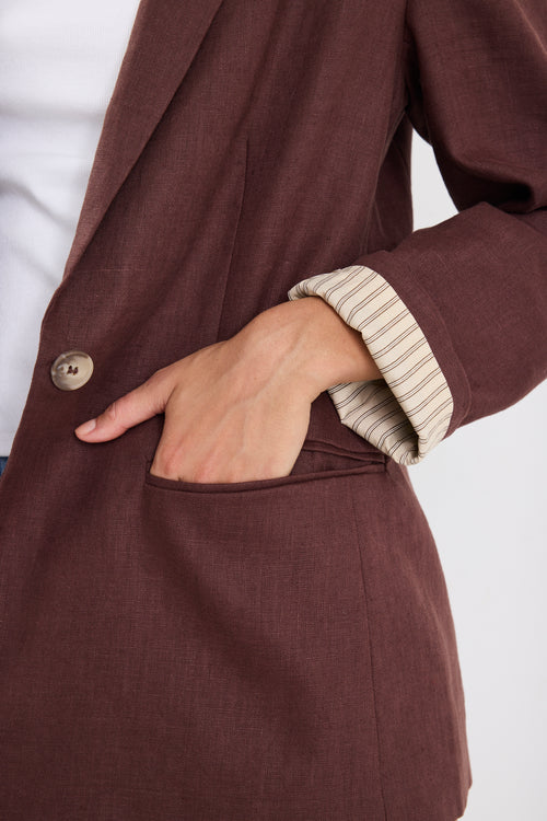 Close-up of a brown coat with a hand in the pocket against a white background
