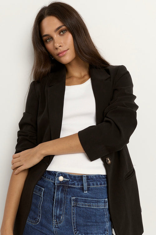 model wears a black blazer with blue jeans