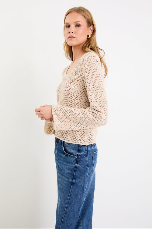 Woman wearing a light crochet knit and blue jeans