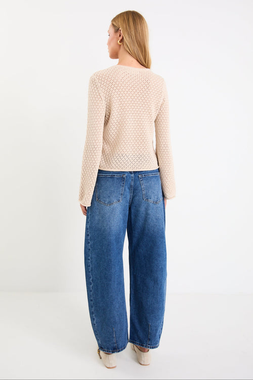 Woman wearing a light crochet knit and blue jeans