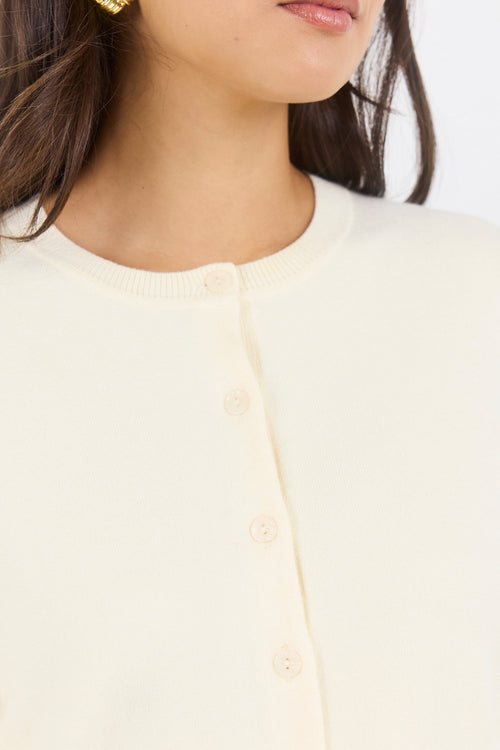 Close-up of a person wearing a light-colored cardigan with a blurred background