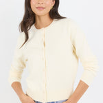 Woman wearing a light-colored cardigan and blue jeans against a white background