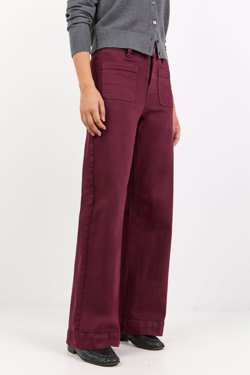 Person wearing burgundy pants and a gray cardigan on a white background