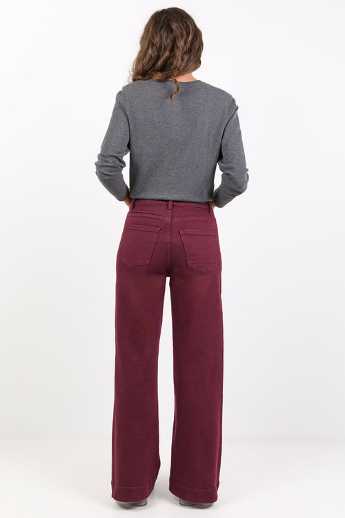 Person wearing a gray sweater and burgundy pants on a white background
