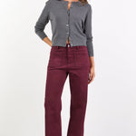 Woman wearing a gray cardigan and burgundy pants on a white background