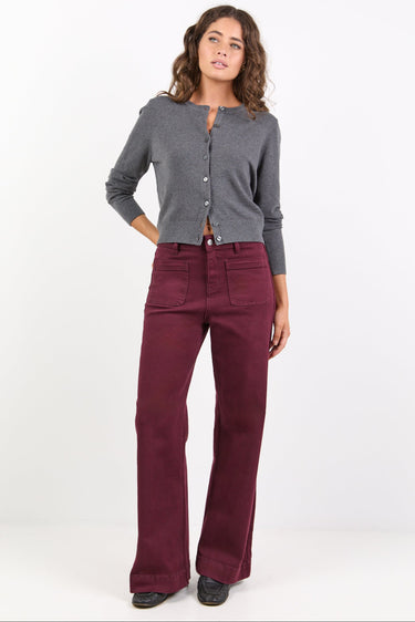 Woman wearing a gray cardigan and burgundy pants on a white background