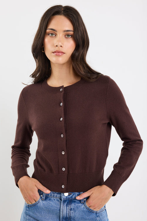 Woman wearing a brown cardigan over a blue top on a white background