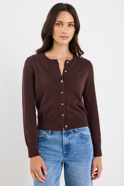 Woman wearing a brown button-up shirt and blue jeans on a white background