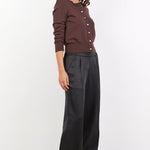 Woman wearing a brown button-up shirt and black wide-leg pants on a white background