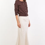 Woman wearing a brown sweater and white pants on a white background
