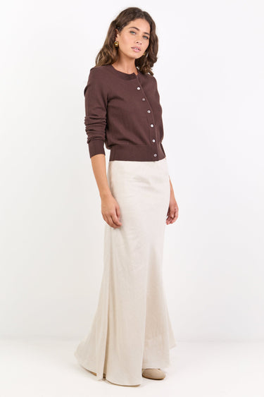 Woman wearing a brown sweater and white pants on a white background