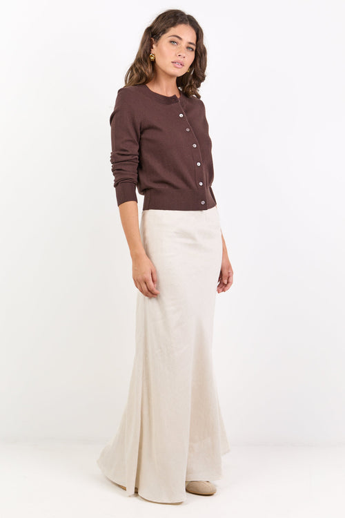 Woman wearing a brown sweater and white pants on a white background