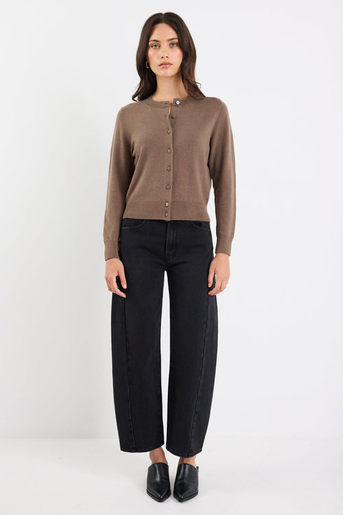 Woman wearing a brown long-sleeve shirt and black pants on a white background