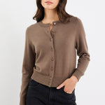 Woman wearing a brown cardigan and black pants against a white background