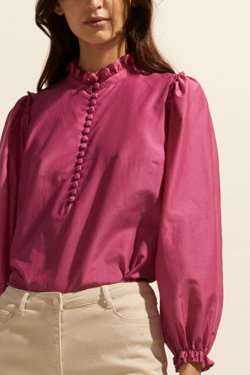 model wears a pink blouse with cream jeans