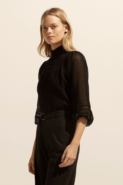 model wears a black blouse with black pants