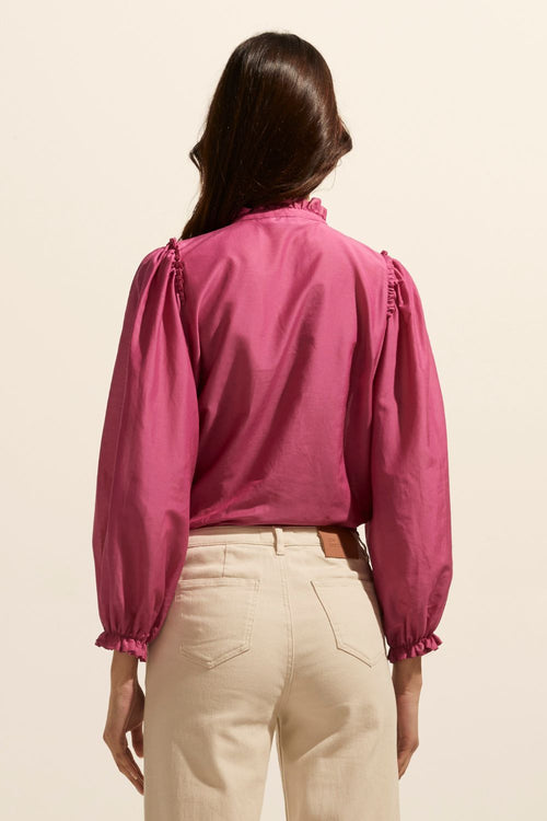 model wears a pink blouse with cream jeans