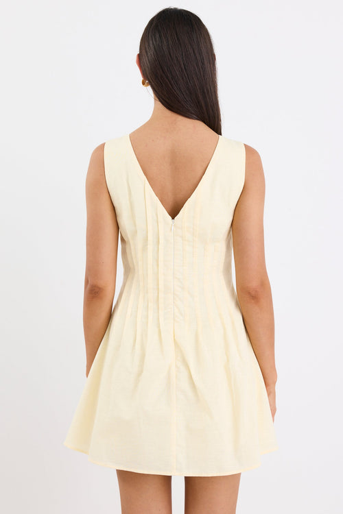 Woman wearing a light yellow dress with a V-neckline on a white background