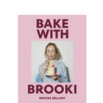 Book cover of 'Bake with Brooki' by Brooke Bellamy with a pink background and photo of a woman holding a cake.