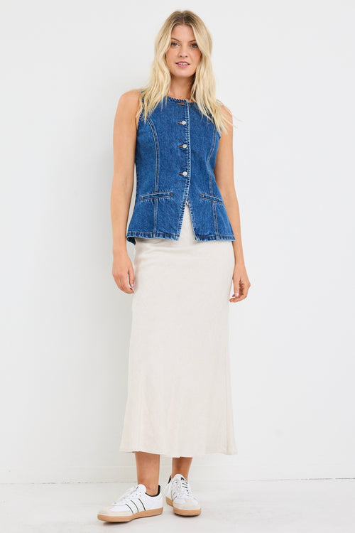 model wears a blue denim vest with a beige linen midi skirt