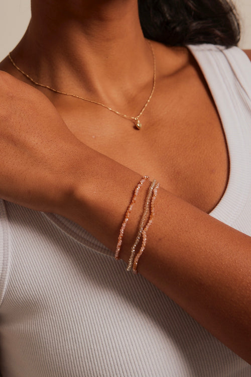 model wearing peach beaded set of bracelets