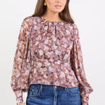 Woman wearing a floral blouse and blue jeans against a white background