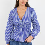 Woman wearing a blue and white striped blouse with long sleeves on a white background