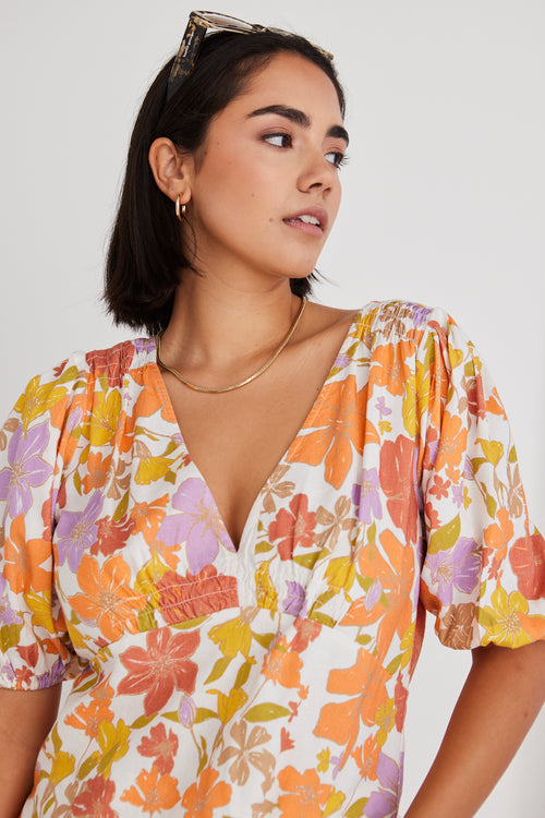model wearing floral orange and yellow top