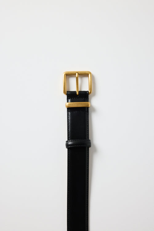 Black leather belt with a gold buckle on a white background