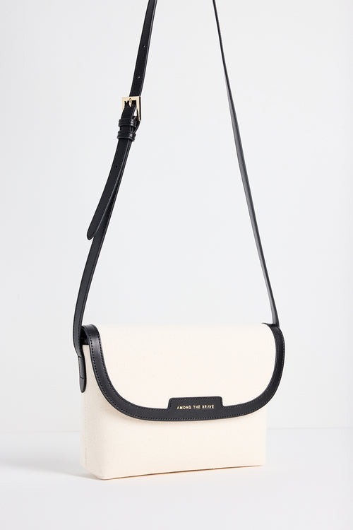 A cream-colored crossbody bag with a black strap and trim