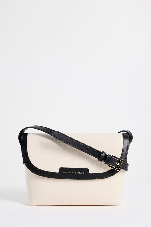 A cream-colored crossbody bag with a black strap and trim