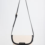 A cream-colored crossbody bag with a black strap and trim