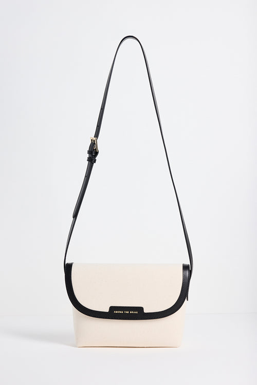 A cream-colored crossbody bag with a black strap and trim