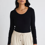 Model wears black long sleeve top with beige pants