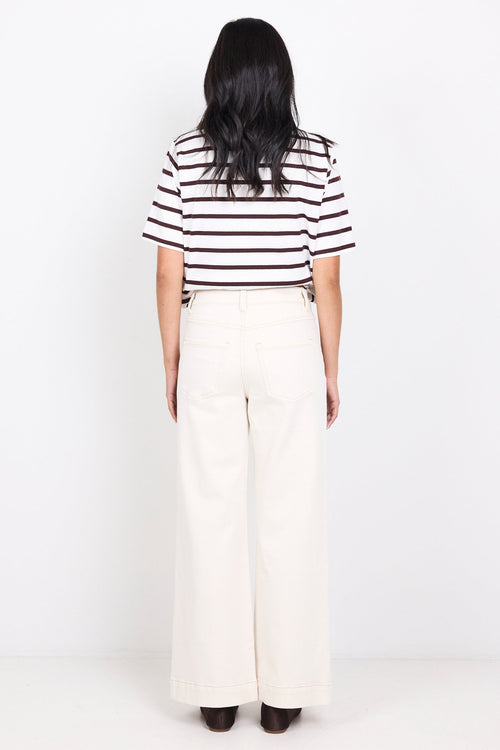 Person wearing a black and white striped shirt and white pants on a white background