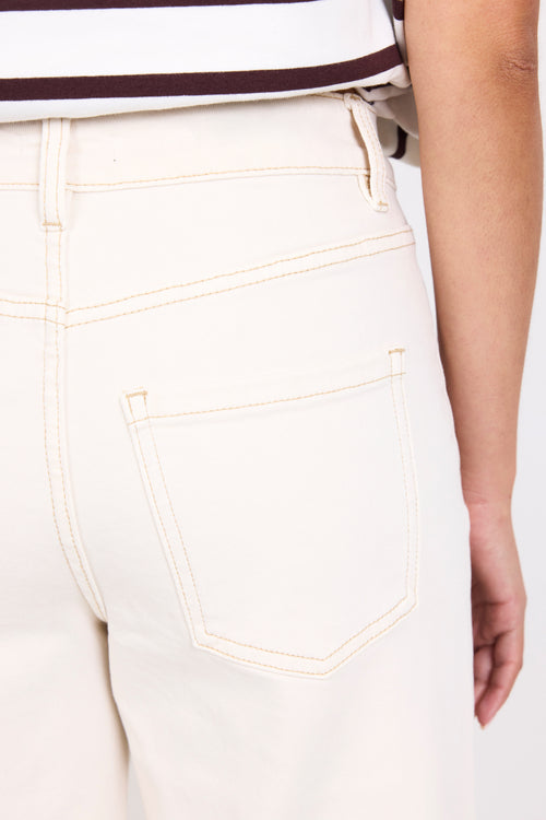 Close-up of a person wearing white pants with a plain background