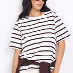 Woman wearing a black and white striped shirt with white pants on a white background